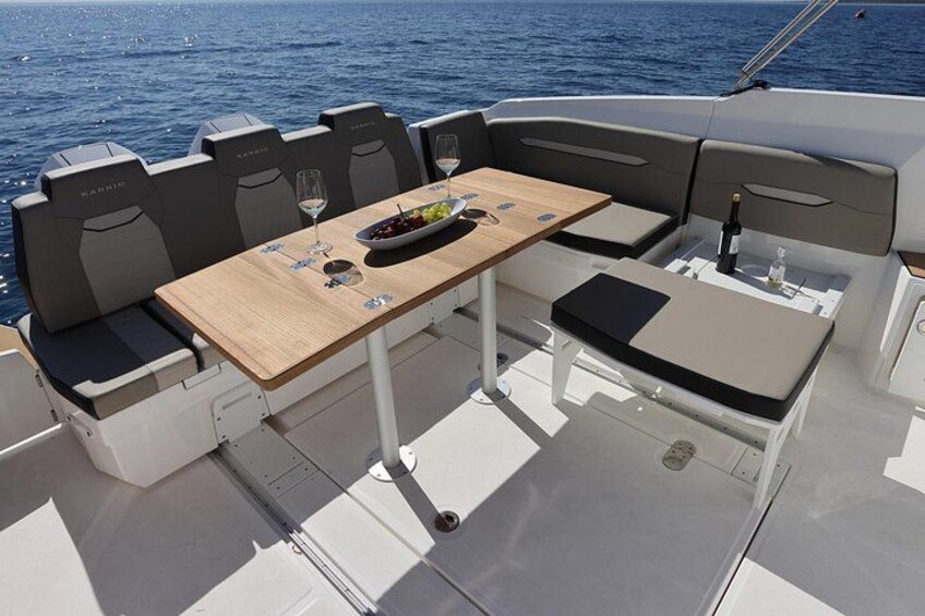A boat with a table and seating area, a bottle of wine, and a bowl of fruit. 5