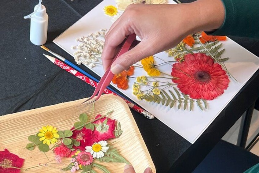 A person arranging dried flowers on a white surface. 3