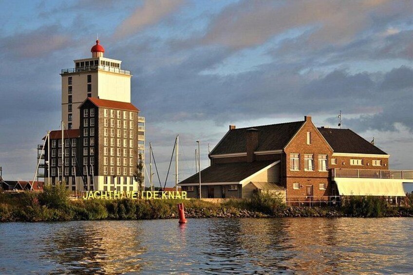 A lighthouse, a building with a red roof, and a river. 1