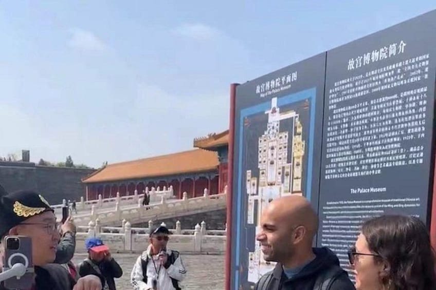 Un gruppo di persone presso un sito storico con un grande cartello informativo sul Museo del Palazzo. 5
