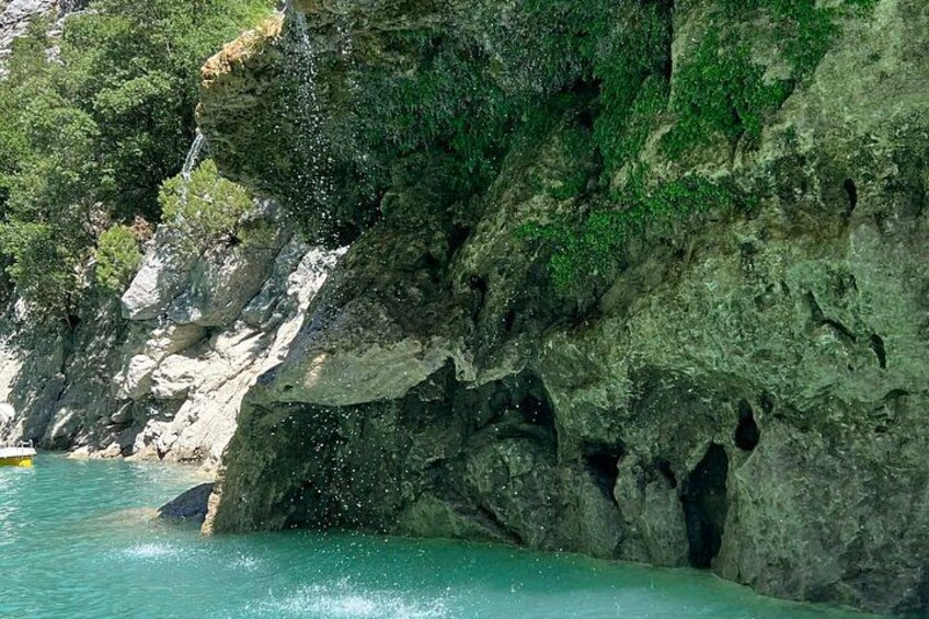 A rocky coastline with a waterfall, clear turquoise water, and lush greenery. 3