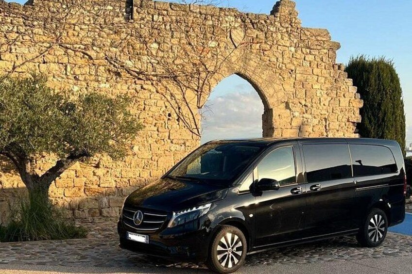 A black van parked in front of a stone archway. 2