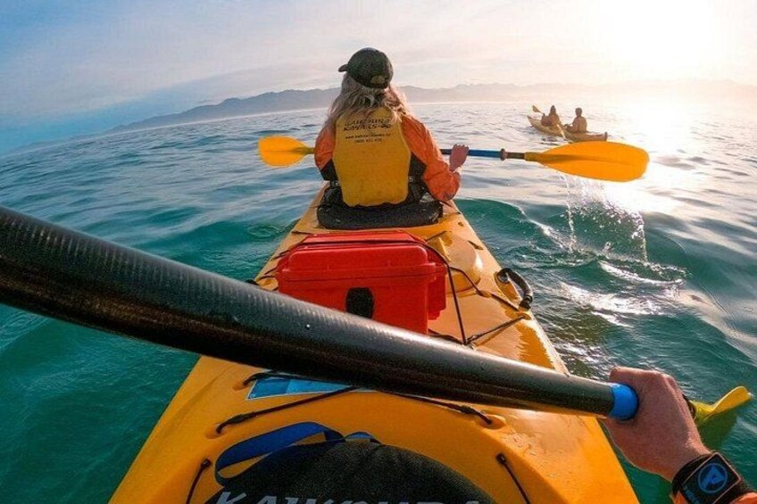 A person kayaking on a calm sea with another kayak in the background. 3
