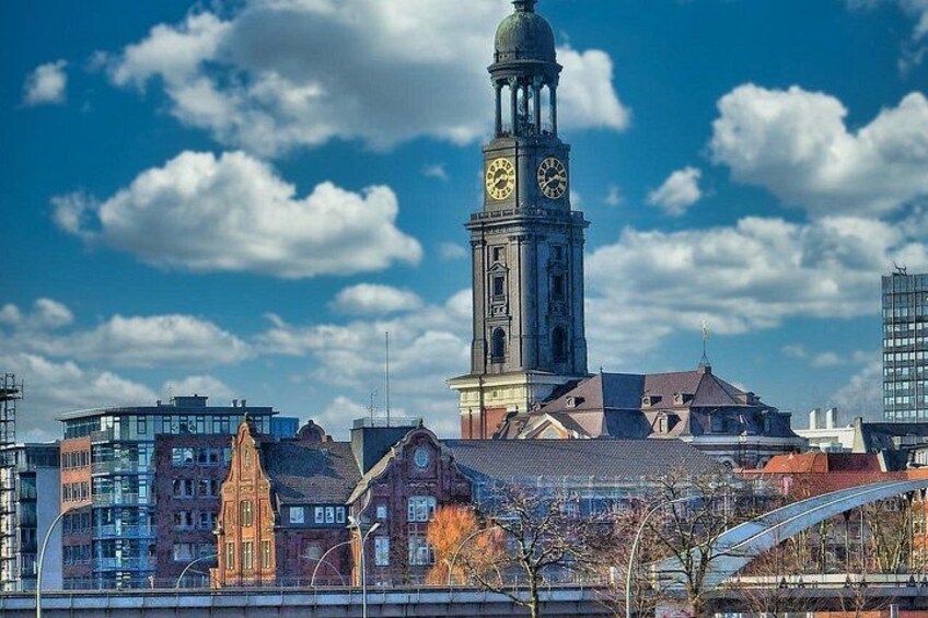 A cityscape with a prominent clock tower, modern buildings, and a clear blue sky. 3