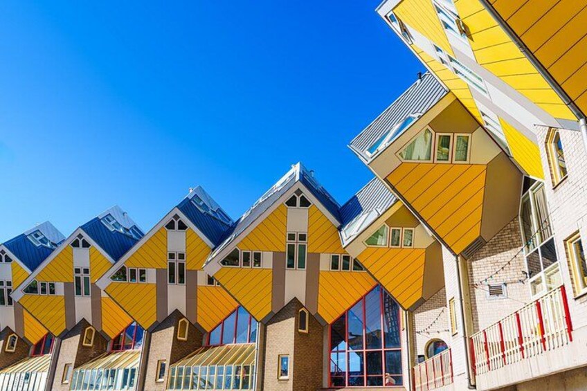 En række farverige, usædvanligt formede huse med gule og blå tage mod en klar blå himmel. 5