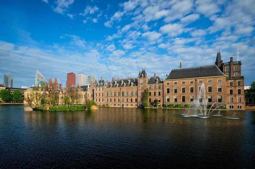 En historisk bygning med en springvand foran, en flod og en bro i baggrunden. 4