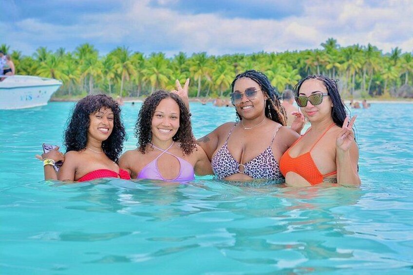 Cuatro personas en una piscina turquesa, con palmeras al fondo. 4