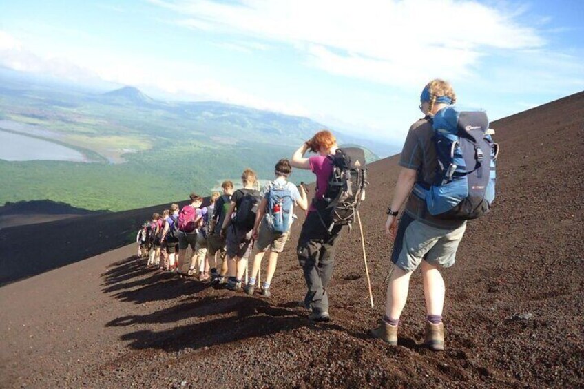 A group of hikers ascending a volcanic slope with a view of distant landscapes. 4