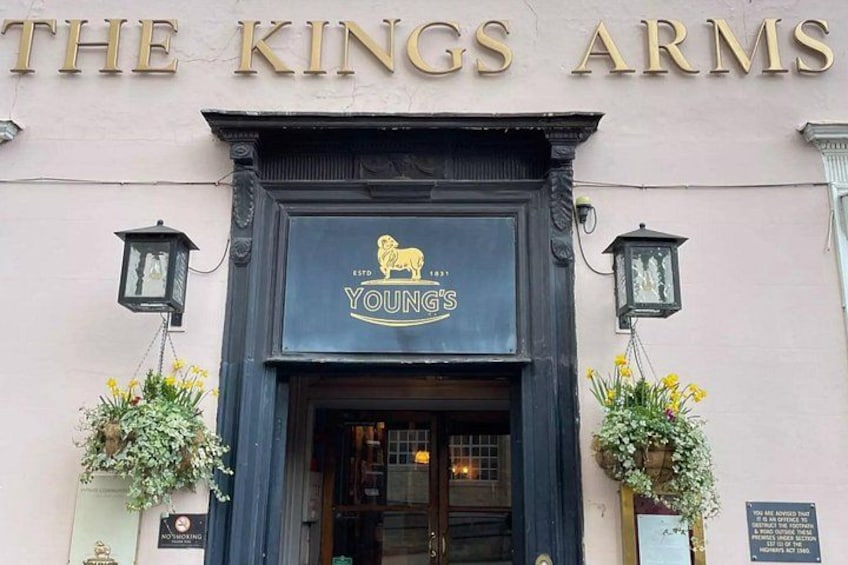 The exterior of The King's Arms pub with a black signboard, two lanterns, and flower boxes. 5