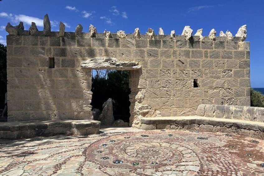 A stone wall with a circular mosaic floor and a large archway. 5