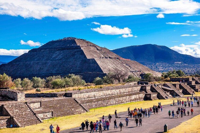 Eine große Pyramide, eine stufenförmige Struktur und eine Menschenmenge. 1