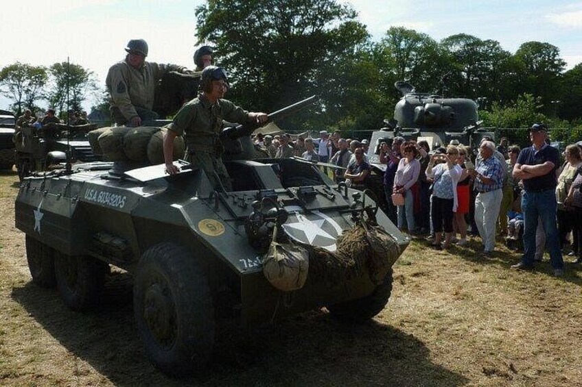 A military vehicle with a mounted gun, surrounded by a crowd of people. 3
