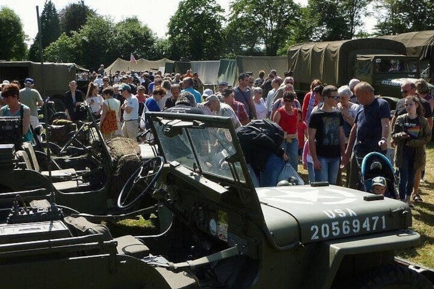 A military vehicle with the number 20569471, surrounded by a crowd of people. 4