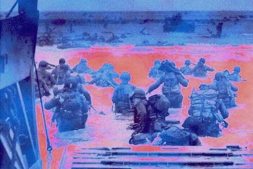 Soldiers in combat gear on a beach with a ship in the background. 1