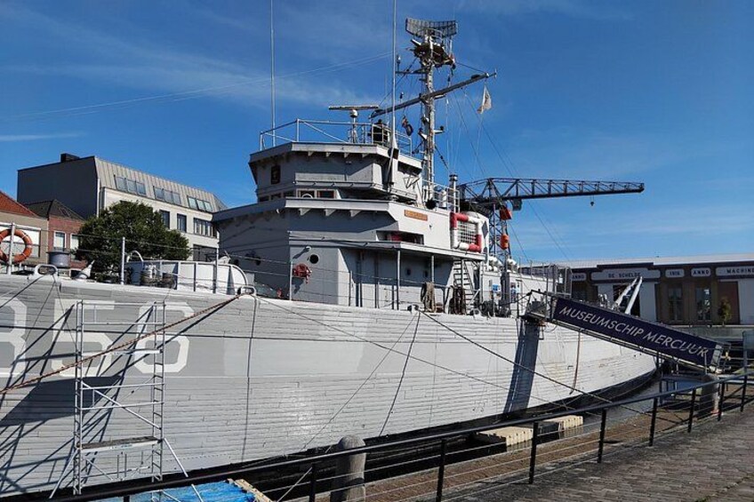 Et stort skib ligger ved kaj i en havn med skilt til et museum. 3