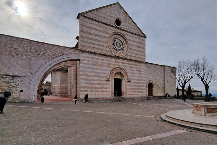 A historic building with a large arched entrance, a clock tower, and a paved courtyard. 5