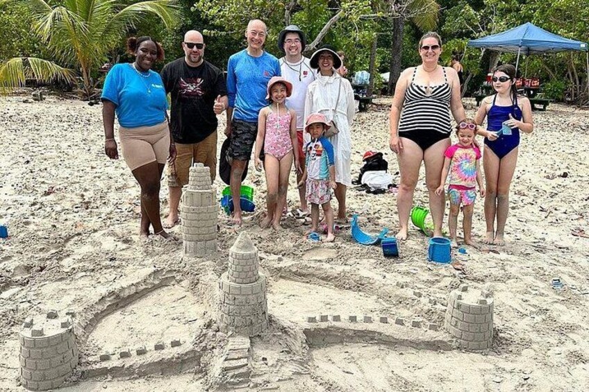 Een groep mensen op het strand, met zandkastelen. 1