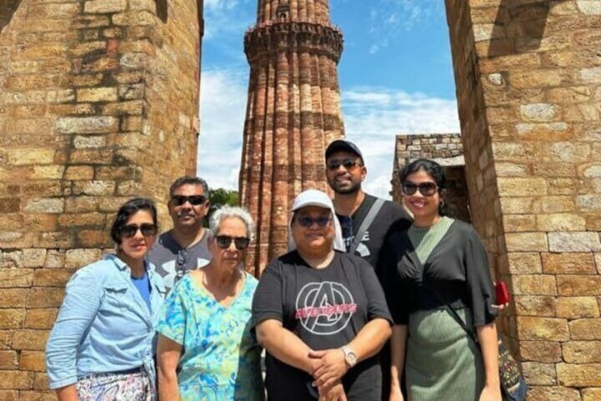 A group of people standing in front of an ancient brick structure with a tall, narrow tower. 1