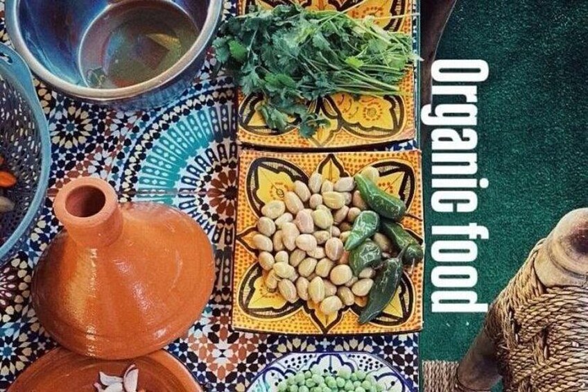 Een Marokkaanse tafel met een terracotta pot, kleurrijke tegels en een schaal met noten en groenten. 2