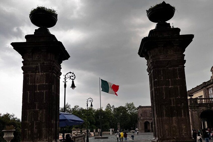 Un monumento histórico con dos columnas, una bandera y un arco. 2