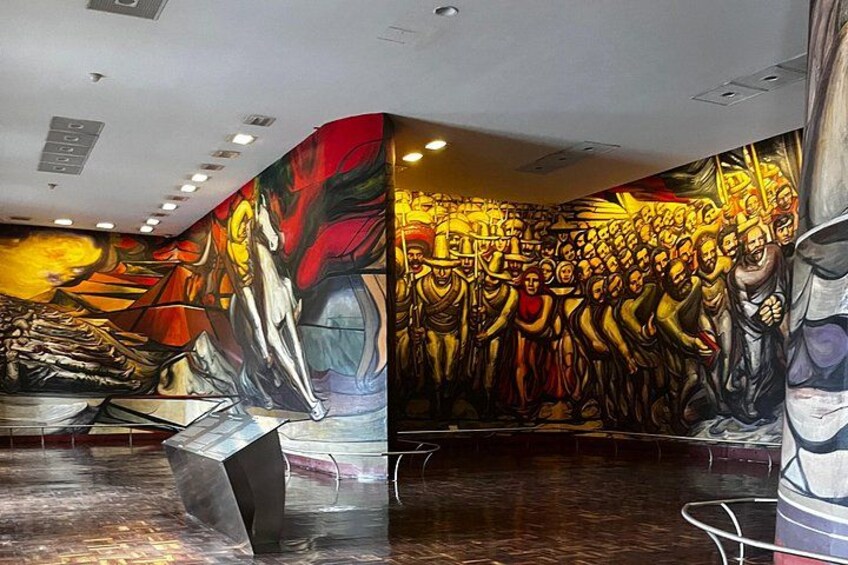Un mural con arte abstracto y figurativo, una pared curva y un piso reflectante. 5