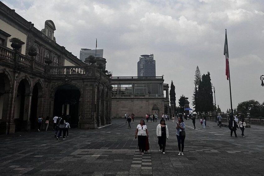 Un edificio histórico con arcos, una bandera y un rascacielos moderno al fondo. 4