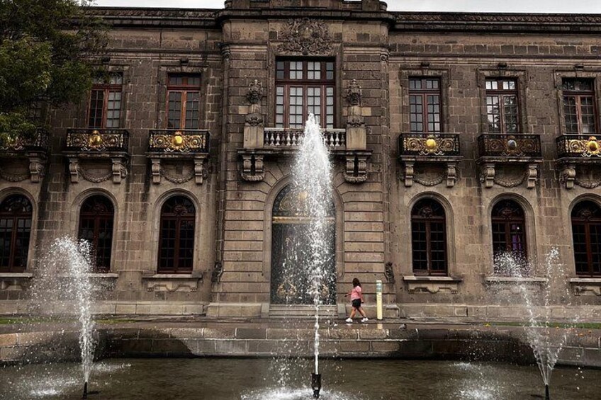 Un edificio histórico con balcones ornamentados y una fuente central. 3
