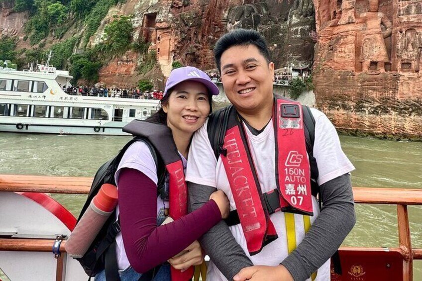 Two people wearing life jackets and a boat in the background. 3