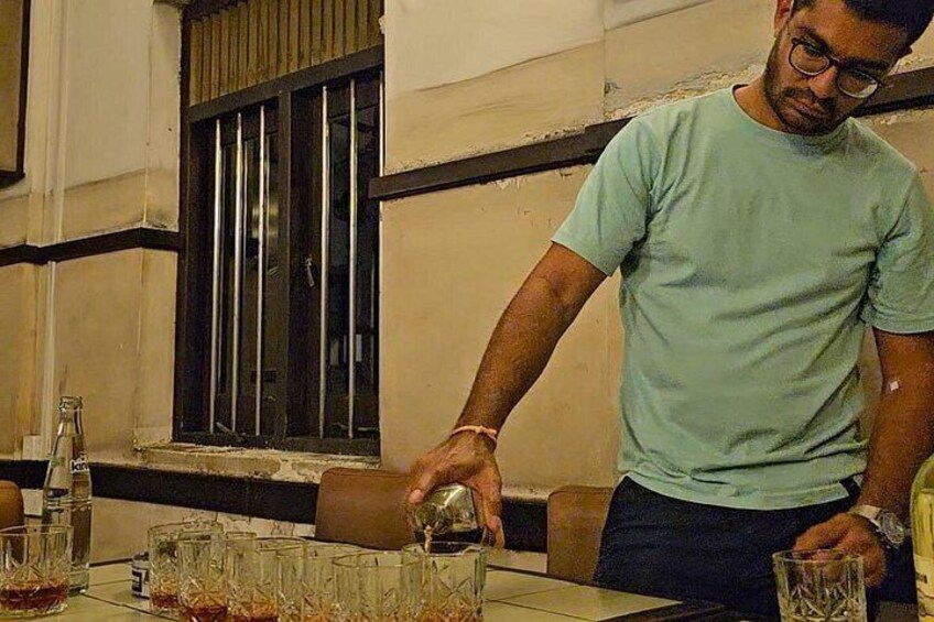 Una persona sirve una bebida en un vaso sobre una mesa con varios vasos. 3