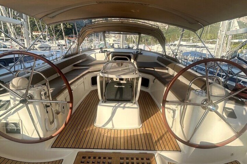 Het dek van een boot met twee stuurwielen, een centraal console en een houten vloer. 4