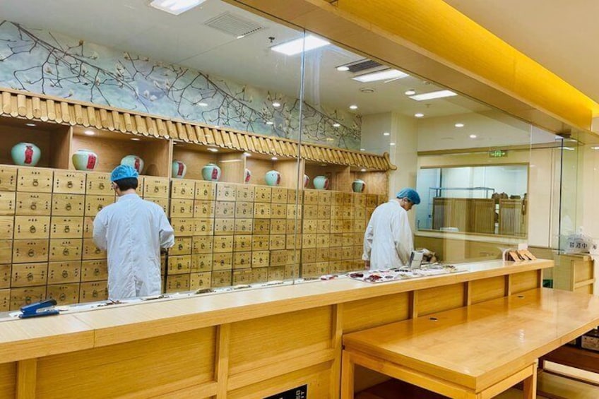 A kitchen with chefs preparing food, wooden cabinets, and a long counter. 3