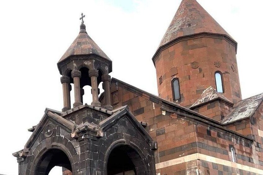 En kirke med et markant klokketårn og en mindre bygning ved siden af. 3