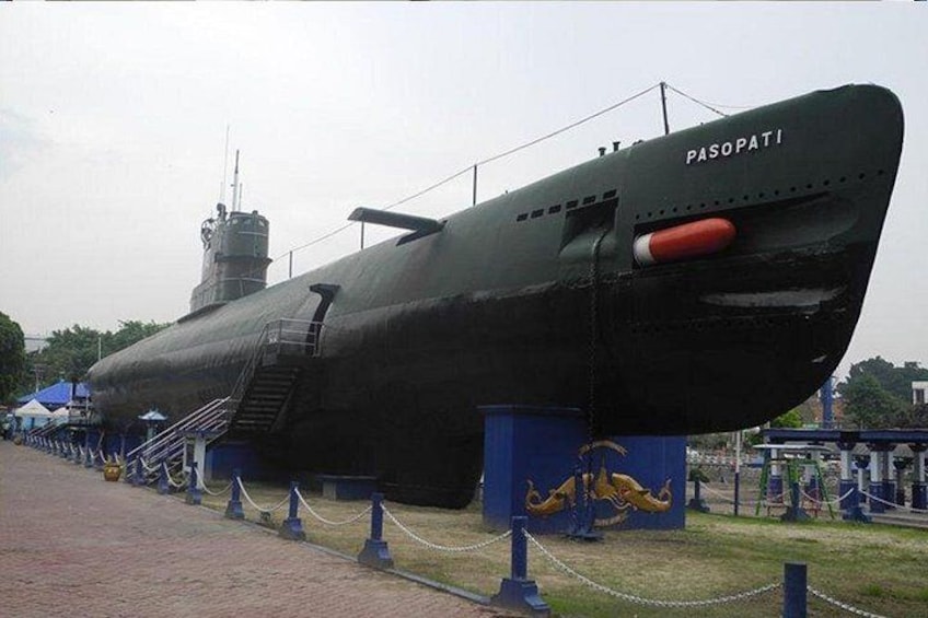A large submarine named PASOPATI on display, surrounded by a chain-link fence and a grassy area with a sculpture. 2