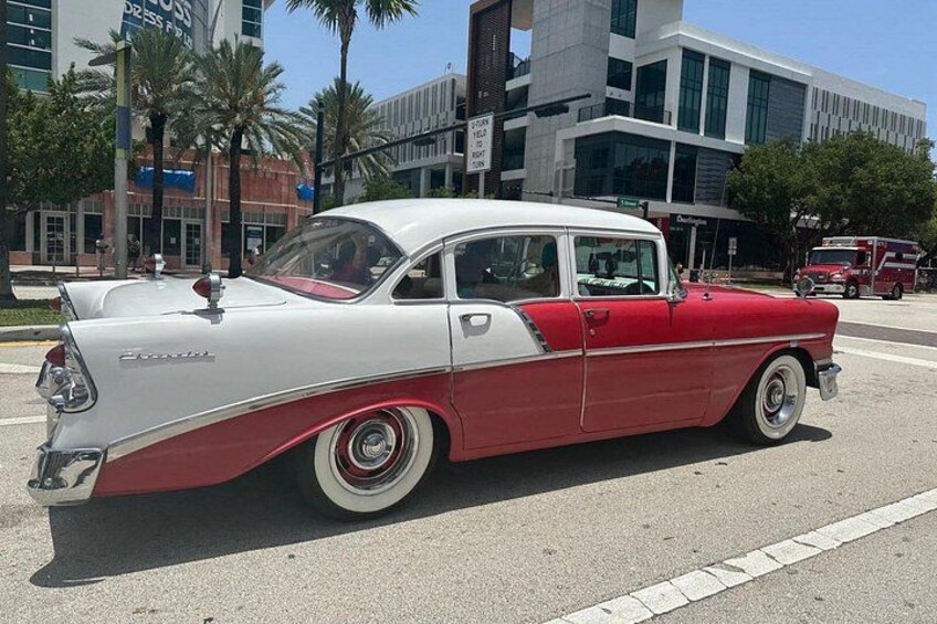 A vintage red and white car parked on a city street. 1