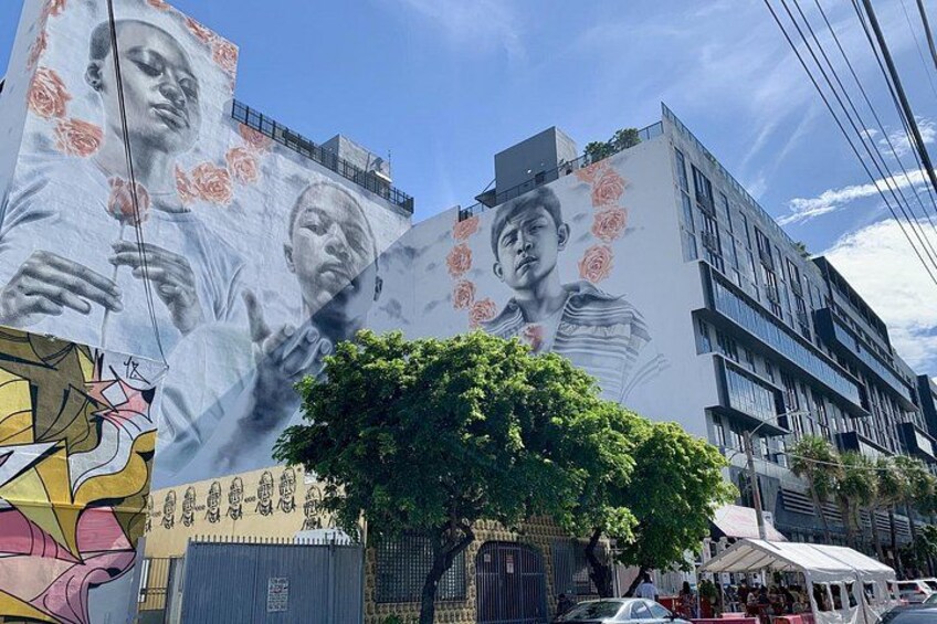 A mural on a building with a tree in front. 2
