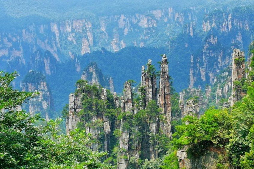 A mountainous landscape with tall, narrow rock formations and dense green foliage. 2