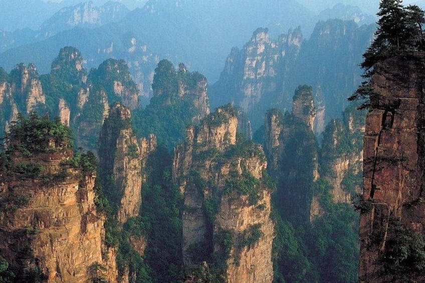A mountainous landscape with tall, narrow rock formations and dense green vegetation. 5