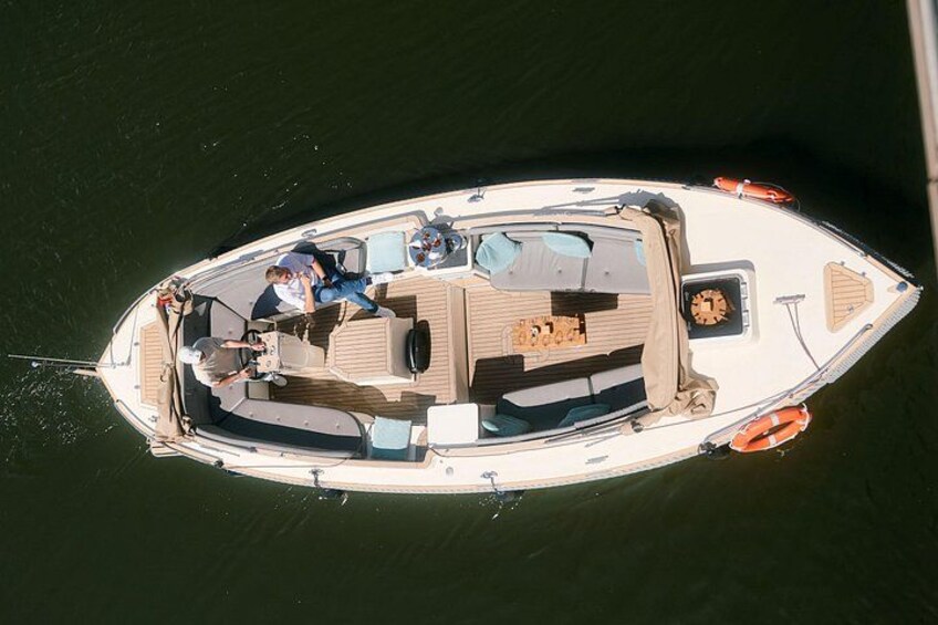 A small boat with two people on board, a wooden deck, and a motor at the stern. 1