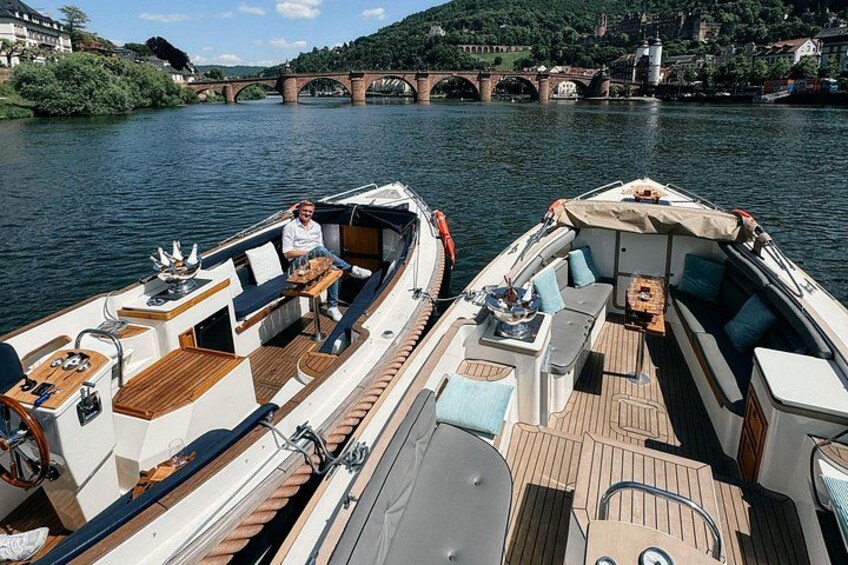 Two boats docked on a river with a bridge in the background. 2