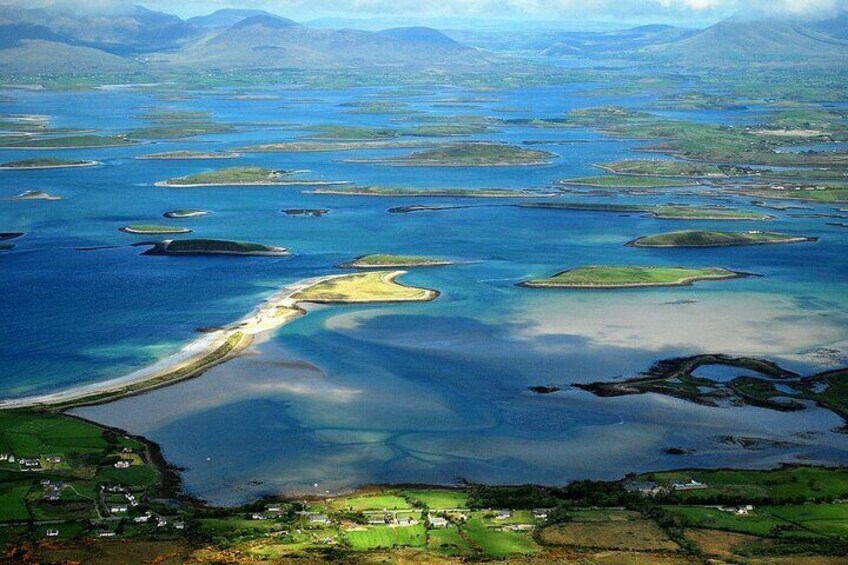 An aerial view of a coastal landscape with a bay, small islands, and a sandy beach. 2