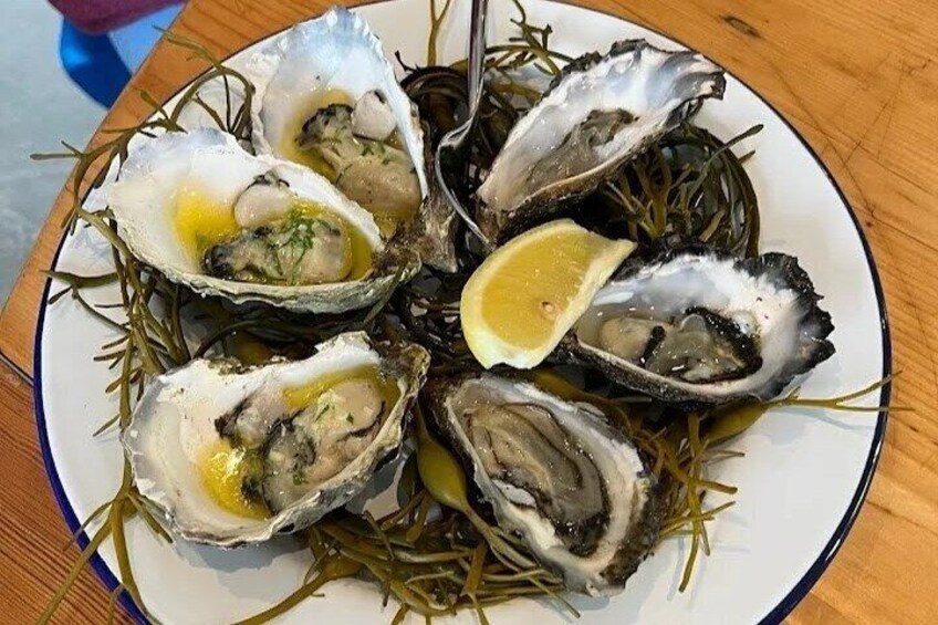 A plate of oysters with lemon wedges and herbs. 3
