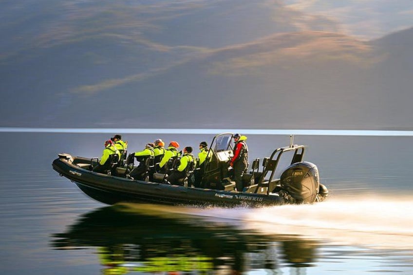 Een boot met verschillende mensen die zwemvesten en helmen dragen, vaart over stil water. 2