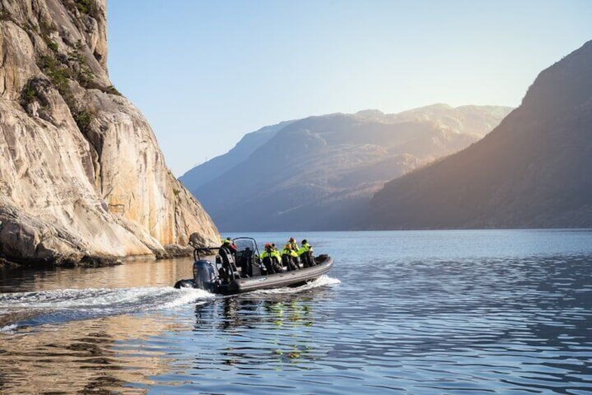 A boat carrying people near a rocky shoreline with mountains in the background. 4