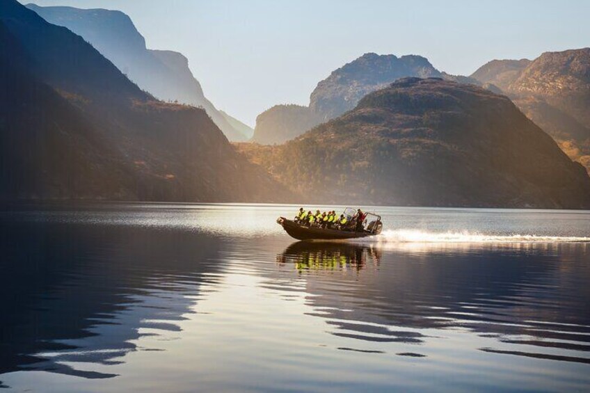 A boat with people on a calm lake surrounded by mountains. 4