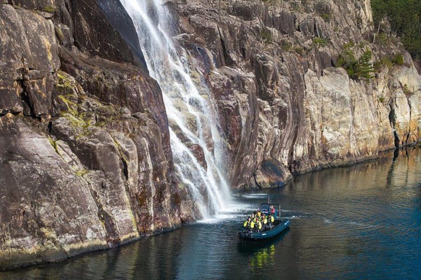 Een waterval, rotsachtige kliffen en een boot met mensen. 1