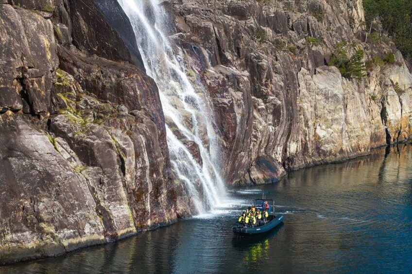 A boat with people on a river near a waterfall. 1