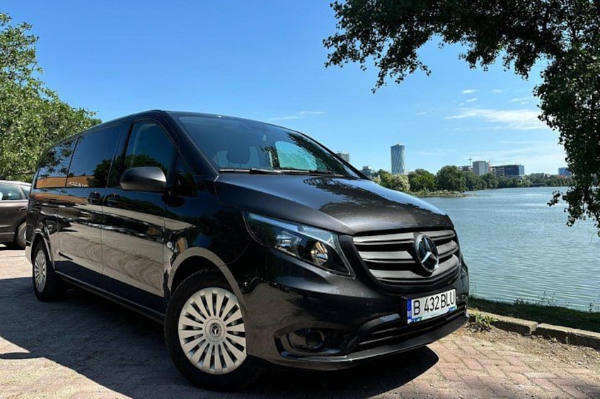 Un SUV Mercedes-Benz negro estacionado frente a la costa, con el horizonte de la ciudad al fondo. 3