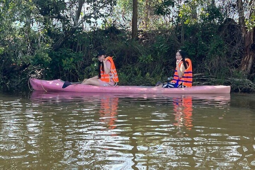 Dos personas en un canoa rosa en un río rodeado de vegetación. 3