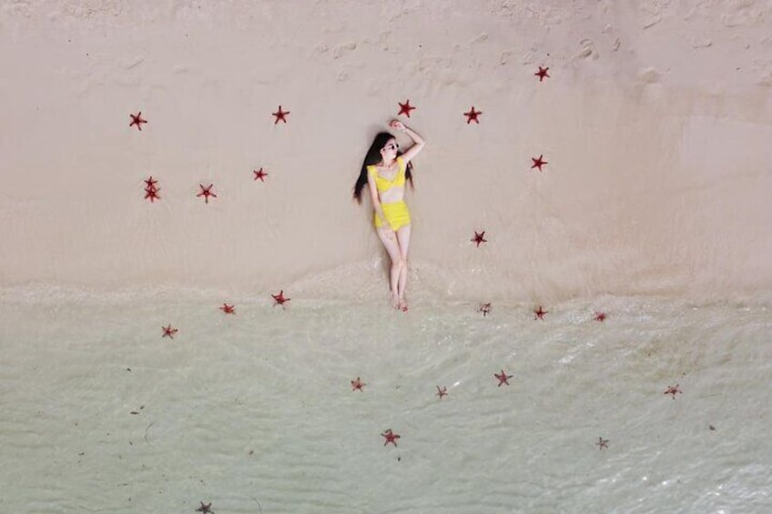 Una persona con traje de baño amarillo de pie en una piscina poco profunda con decoraciones de estrellas rojas en la pared. 5