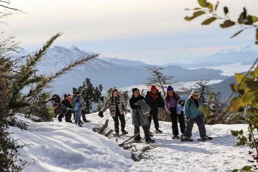 A group of people hiking on a snow-covered mountain trail with a scenic view of mountains in the background. 5